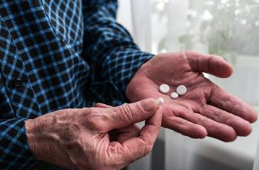 Close-up of an elderly man's hands with pills